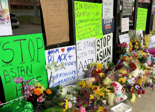 vigil on sidewalk with signs and flowers